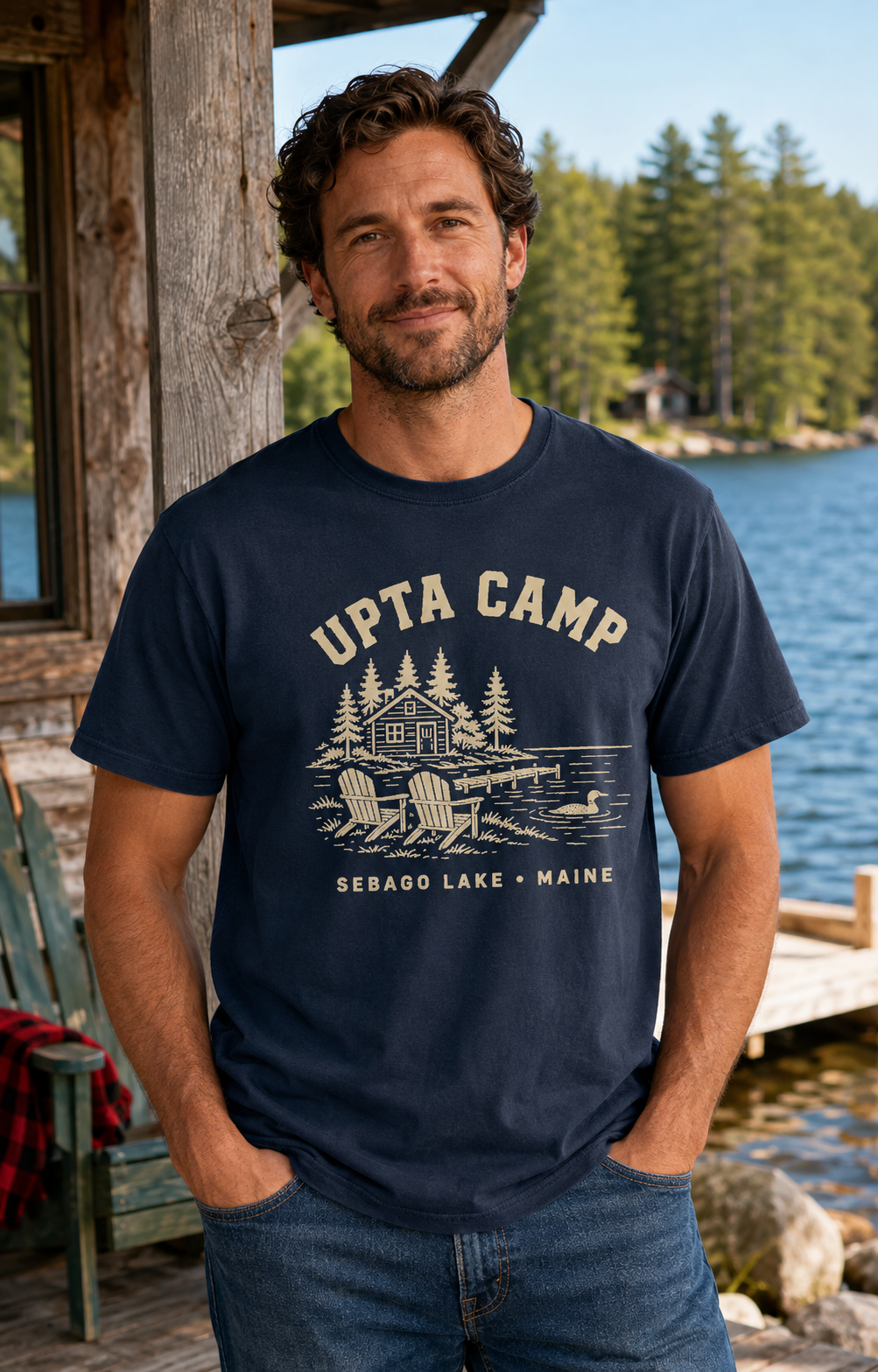 Man wearing a navy Upta Camp Sebago Lake Maine t-shirt at a lakeside camp