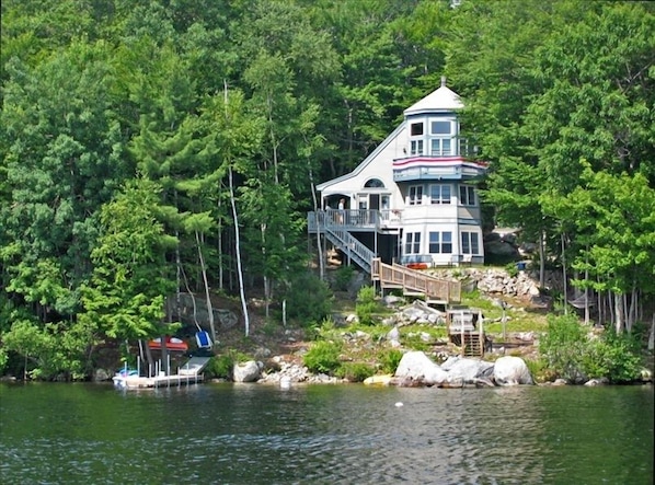 A lakeside cabin with a dock, surrounded by dense forest.