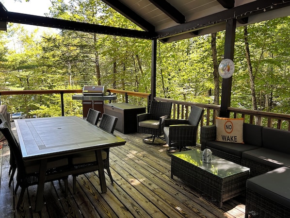 An outdoor deck with a table and chairs, a grill, and a 'No Wake' sign.