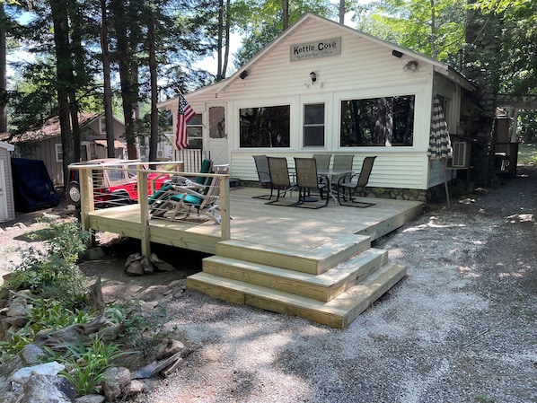 A small building labeled "Kettle Cove Bank and Post Office" with a deck, outdoor seating, and a flag.