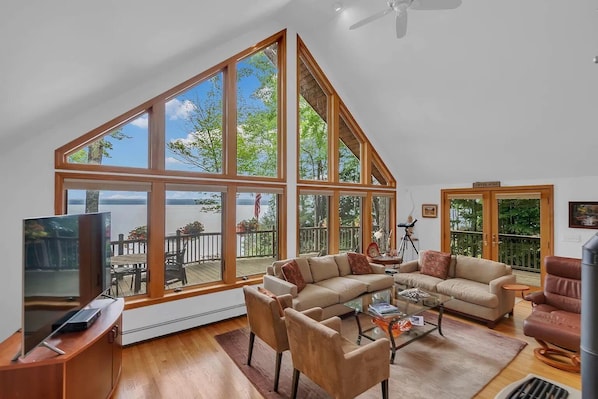 A spacious living room with large windows, a television, and a cozy seating area.