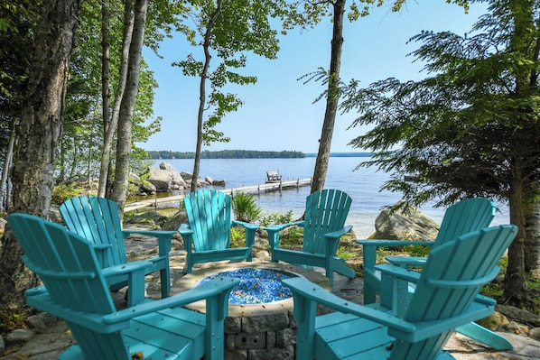 Lakeside chairs, gas firepit and dock at the Frye Island sandy-cove home